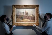 Des employés mettent en place l'oeuvre du peintre néerlandais Vincent Van Gogh "Scène de rue à Montmartre" (1887) au sein de la maison d'enchères Sotheby's à Paris le 24 février 2021