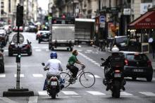A woman rides a bicycle past motorcyclists in Paris, on September 23, 2020.
