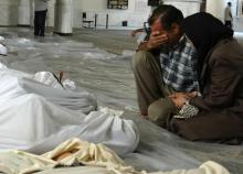 Image fournie par Shaam News Network, un média de l'opposition syrienne, montrant un couple se recueillant devant les victimes d'une attaque au gaz toxique selon l'opposition syrienne, le 21 août 2013