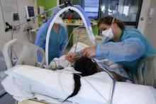 Des soignantes s'occupent d'un patient atteint du Covid-19 dans l'unité de soins intensifs de l'hôpital Delafontaine, le 29 mars 2021 à Saint-Denis, près de Paris