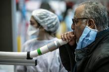 Un homme souffle dans un instrument en expérimentation qui doit permettre de dépister le virus du Covid-19, le 8 avril 2021, au Palais des sports de Lyon