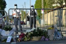 Des policiers en faction le 26 avril 2021 à Rambouillet derrière des barrières au pied desquelles ont été déposées des fleurs en hommage à leur collègue tuée