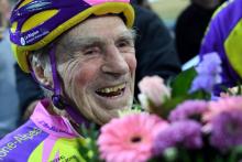 Le cycliste centenaire amateur français Robert Marchand, 106 ans, reçoit un bouquet de fleurs après avoir achevé un 4.000 mètres au vélodrome de Saint-Quentin-en-Yvelines, le 11 février 2018
