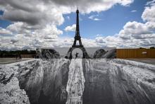 Une femme saute sur l'esplanade du Trocadéro, en face de la Tour Eiffel, au-dessus d'un trompe-l'oeil de l'artiste français de street-art JR, le 19 mai 2021 à Paris