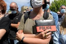 Une officier de police arbore son badge police le 9 mai 2021 à Avignon lors de l'hommage à son collègue tué