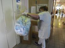 Une infirmière récupère un sac plastique contenant des masques chirurgicaux à recycler, le 10 avril 2021 à l'hôpital Saint-Antoine, à Paris
