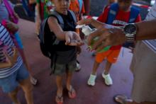 Des élèves se lavent les mains avec du gel hydroalcoolique en arrivant à l'école primaire Manotahi de Punaaui, en Polynésie française, le 23 septembre 2021