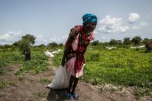 Au Soudan du Sud, une femme ramasse un sac de céréales distribué par le Programme alimentaire mondial, en juillet 2018
