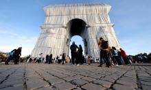 Des personnes devant l'Arc de Triomphe "empaqueté", oeuvre posthume de Christo et de son épouse Jeanne-Claude, le 30 septembre 2021 à Paris