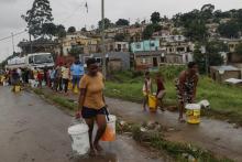 Des résidents du quartier de Bhambayi viennent s'approvisionner en eau potable après la rupture des canalisations ravagées par les inondations, à Durban le 15 avril