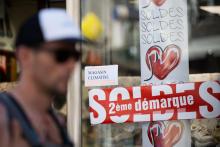Un homme passe devant une vitrine où une affichette indique que le magasin est climatisé, pendant les soldes, le 13 juillet 2022 à Nantes
