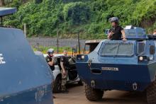 Des policiers anti-émeute à bord de véhicules blindés surveillent une zone à Tsoudzou, près de